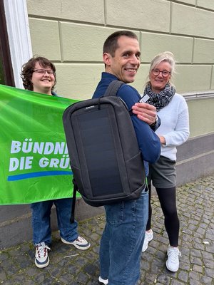 Benjamin Stukenberg (Mitte), Kreisvorsitzender der Stormarner Grünen, mit geschultertem Solar-Rucksack. Neben ihm die Vorstandsmitglieder Angela Tsagkalidis (r.) und Lorenzo Dal Molin. 